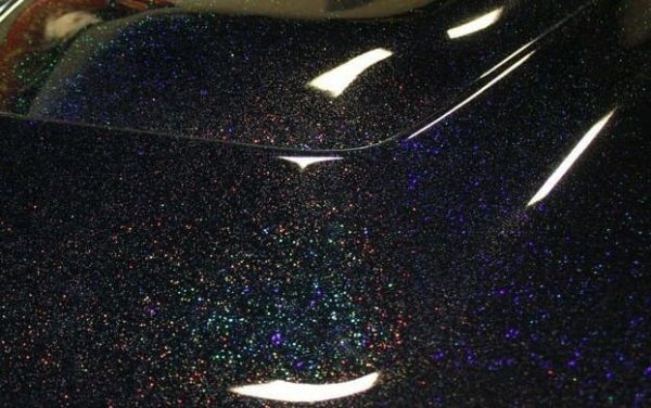Black holographic metal flake on a car hood. Holographic flakes.